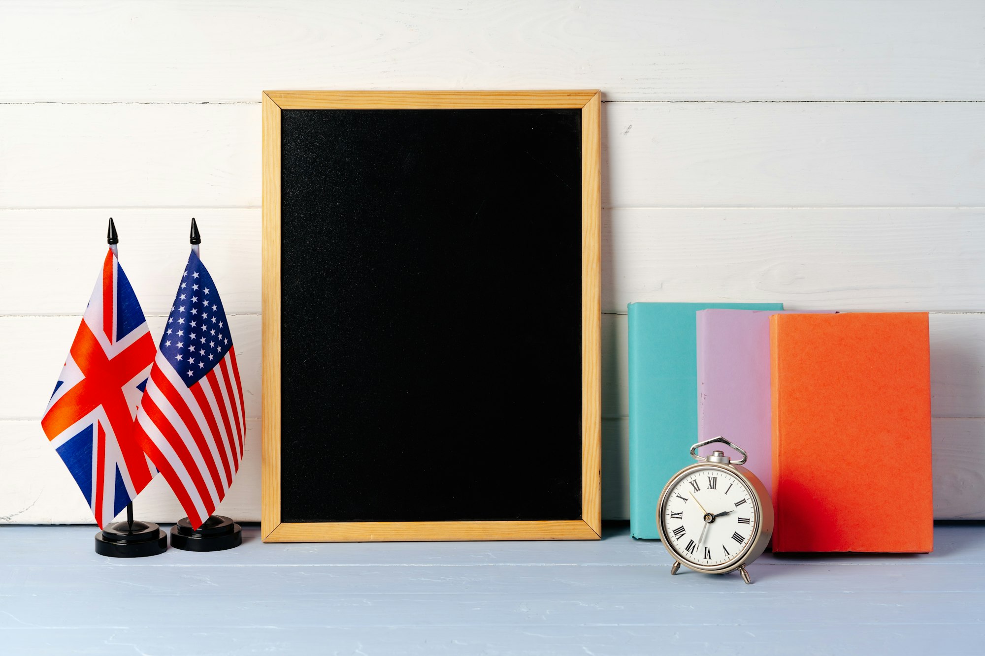 Blackboard with books, alarm clock and flags of USA and Great Britain. Education abroad concept